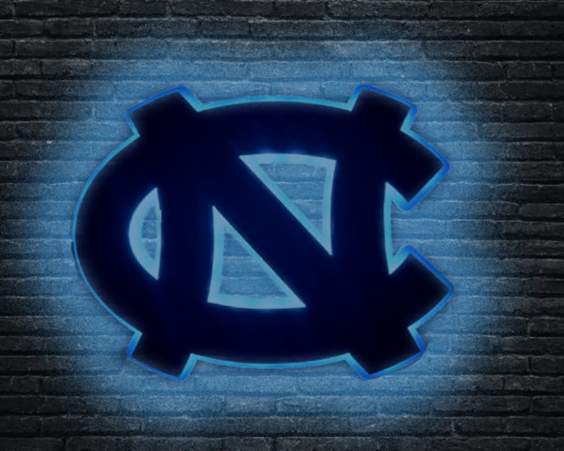 Puede incluir: Un letrero de ne&oacute;n azul y negro con las letras "NC" en una fuente estilizada. El letrero est&aacute; iluminado con una luz azul brillante.