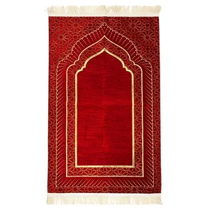 Peut inclure: Un tapis de prière rectangulaire d'un rouge profond présentant un motif central en forme d'arche mihrab souligné d'or. La bordure affiche des motifs géométriques complexes et un motif pointillé, avec des franges crème aux extrémités.