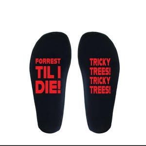 May include: A pair of black insoles with red text. One insole reads "FORREST TIL I DIE!" and the other reads "TRICKY TREES! TRICKY TREES!". The insoles are designed to fit inside shoes.