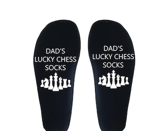 May include: A pair of black socks with white text that reads "Dad's Lucky Chess Socks" and a white graphic of chess pieces.