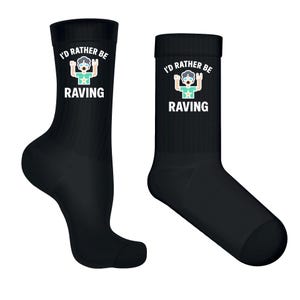 May include: Two black crew socks. Each sock features the text "I'd rather be raving" above a graphic of a person with their arms raised. The word "RAVING" is below the graphic. The graphic is in white, blue, and green.