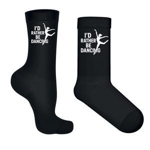 May include: A pair of black socks featuring the text "I'd Rather Be Dancing" and a white ballerina graphic. These crew-length socks are made from a soft material. Ideal for dancers or those who enjoy dancing.