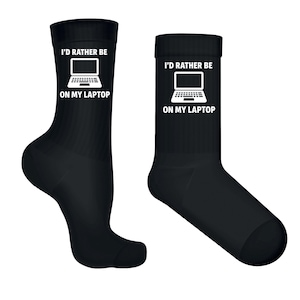 Könnte beinhalten: Zwei schwarze Socken mit dem Text "I'D RATHER BE ON MY LAPTOP" und einer Laptop-Grafik in Weiß. Die Socken sind knöchellang und aus weichem Material. Die Socken sind für Komfort und Stil konzipiert.