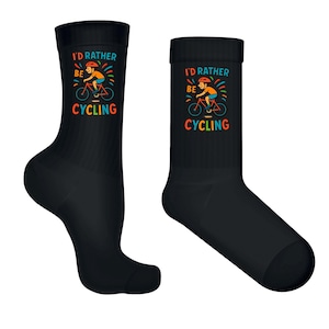 May include: Two black crew socks featuring the text "I'D RATHER BE CYCLING" and a cyclist graphic. The cyclist wears a helmet and rides a bicycle. The text and graphic are in vibrant colours.