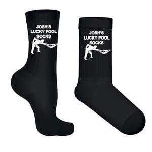 May include: Two black crew socks. Each sock has the text "JOSH'S LUCKY POOL SOCKS" in white, with a white graphic of a person playing pool. The socks are shown against a white backdrop.