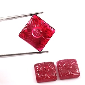 Puede incluir: Dos cabujones de piedra preciosa tallados de forma cuadrada roja con un diseño floral. Los cabujones miden aproximadamente 2,5 cm de lado.