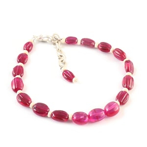Könnte beinhalten: Ein Armband aus rosa und weißen Perlen mit einem silbernen Verschluss.