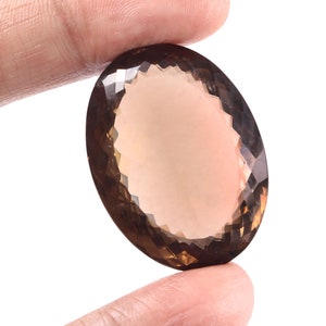May include: A large, oval-shaped, faceted, smoky quartz gemstone with a light brown color.