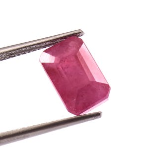 Może przedstawiać: Różowy kamień szlachetny o prostokątnym szlifie szmaragdowym. Kamień szlachetny jest trzymany przez pęsetę.
