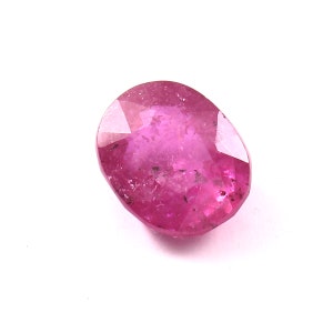 May include: A vibrant pink oval-shaped gemstone with a faceted cut. The gemstone has a slightly cloudy appearance with some inclusions visible.