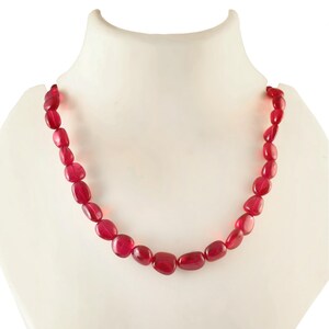 Op de afbeelding: Een ketting gemaakt van gladde, rode edelsteen kralen. De kralen zijn ovaalvormig en hebben een glanzende afwerking.