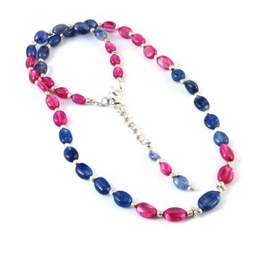 Puede incluir: Un collar de piedras preciosas azules y rosas con cuentas de forma ovalada. El collar está hecho de plata y tiene un cierre de broche.