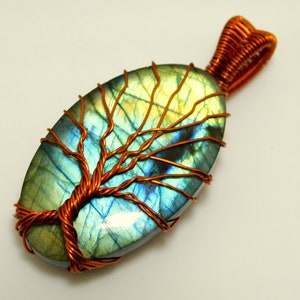 May include: A copper wire tree of life pendant with a blue-green labradorite gemstone. The pendant is oval shaped and has a copper wire bail.