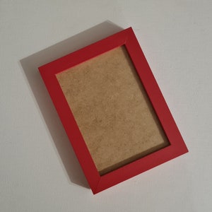 Op de afbeelding: Een rood fotolijstje met een bruine kartonnen achterkant.