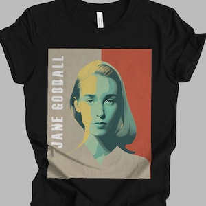 Könnte beinhalten: Schwarzes T-Shirt mit einem Porträt von Jane Goodall. Das Kunstwerk verwendet einen Farbblockstil mit Gelb-, Türkis- und Rottönen. Der Name "JANE GOODALL" ist vertikal auf der linken Seite des Porträts aufgedruckt.