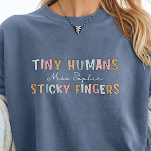 T-shirt humoristique pour maîtresse de maternelle « Petits humains aux doigts collants » - Couleurs confortables - Cadeau personnalisé pour enseignante - T-shirt pour école maternelle