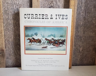 Może przedstawiać: Twarda oprawa książki zatytułowana "CURRIER & IVES CHRONICLES OF AMERICA" z ilustracją zimowej scenerii na okładce. Obraz przedstawia konie ciągnące sanie przez śnieg. Książka leży na drewnianej powierzchni.