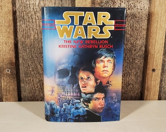 May include: A paperback book cover for "Star Wars: The New Rebellion" by Kristine Kathryn Rusch. The cover features a skull, Luke Skywalker, Princess Leia, and Han Solo.