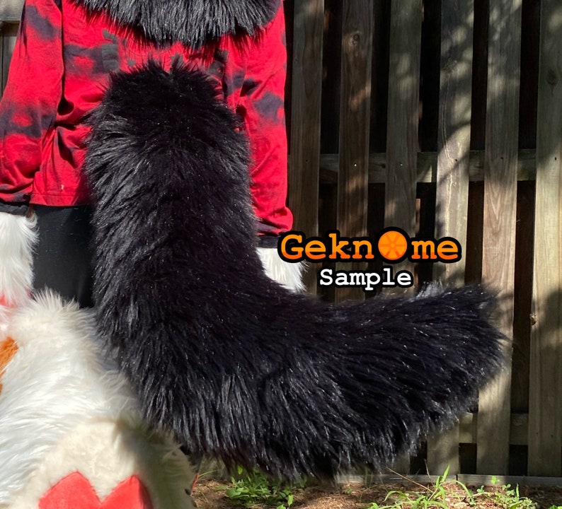 May include: A long, black faux fur tail, likely for a costume or cosplay. The tail is thick and fluffy, with a slight curve. The text "Geknome Sample" is visible in the image.