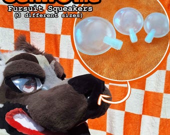 May include: The image features a close-up of a fursuit head with a brown and white pattern, and a red mouth. The image also shows three clear, round squeakers with light blue stems. The text on the image says "Geknome Fursuit Squeakers (3 different sizes)".