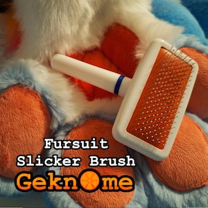 May include: White slicker brush with a blue handle and orange bristles. The brush is lying on a fluffy white and orange fursuit. The text "Fursuit Slicker Brush Geknome" is printed on the fursuit.