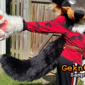May include: A furry costume featuring a black, brown, and white wolf head and tail. The costume includes a red long-sleeve shirt with black tie-dye patterns, black pants, and white paw gloves with pink pads. A brown belt is worn around the waist.