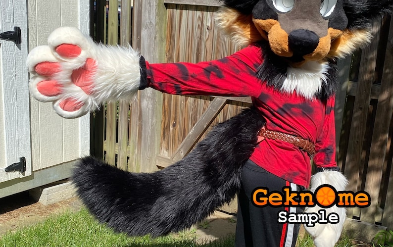 May include: A furry costume featuring a black, brown, and white wolf head and tail. The costume includes a red long-sleeve shirt with black tie-dye patterns, black pants, and white paw gloves with pink pads. A brown belt is worn around the waist.