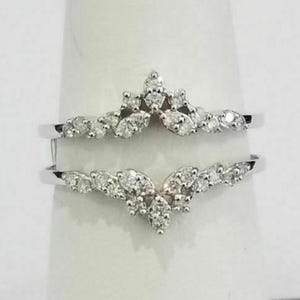May include: Two silver rings with a floral design. Each ring features multiple small, round, and marquise-cut clear gemstones. The gemstones are clustered together to form a leaf-like pattern. The rings are displayed on a white background.