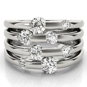 May include: A silver ring with multiple bands and seven round clear gemstones.