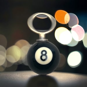 May include: A silver bottle opener shaped like a black eight ball with a white number eight.