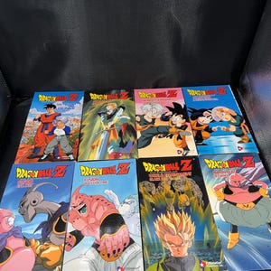 May include: A collection of eight Dragon Ball Z VHS tapes. Each tape features colorful illustrations of characters from the anime series. The titles include "The History of Trunks," "World Tournament," and "Fusion Reborn."