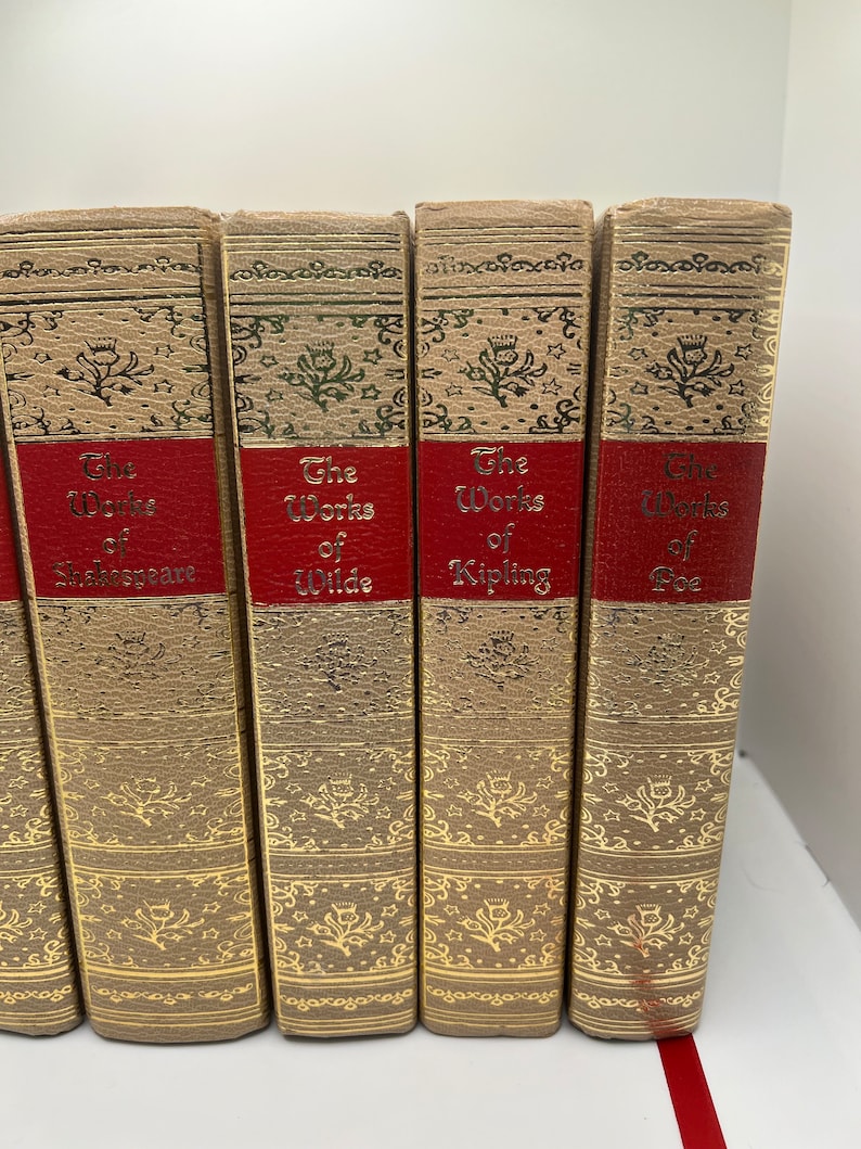 May include: A set of five books with gold-embossed spines and red labels. The labels read "The Works of Shakespeare", "The Works of Wilde", "The Works of Kipling", and "The Works of Poe".