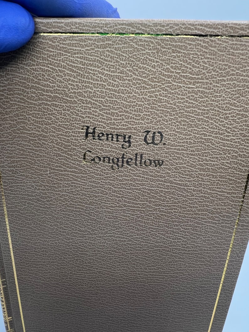 May include: A brown leather-bound book with gold accents and the text "Henry W. Longfellow" embossed on the front cover.