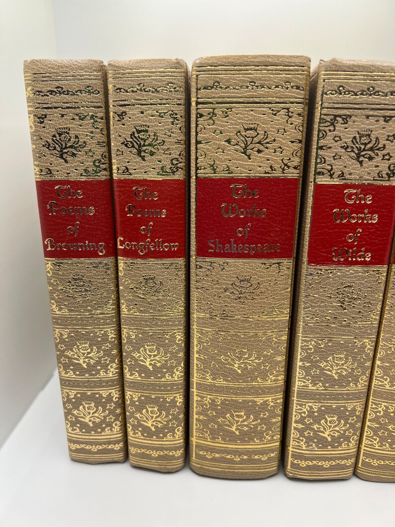 May include: A set of five vintage hardcover books with gold accents and red spines. The titles are "The Poems of Browning", "The Poems of Longfellow", "The Works of Shakespeare", and "The Works of Wilde".