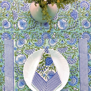 May include: A green and blue floral tablecloth with a white plate and a blue and white striped napkin. The tablecloth has a border of blue and white stripes.