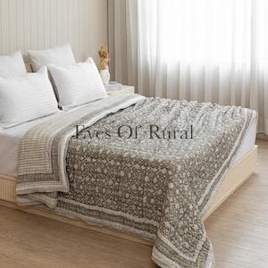Könnte beinhalten: Ein Bett mit weißen Kissen und einer floral gemusterten Steppdecke. Die Steppdecke ist hauptsächlich olivgrün mit einem weißen Blumenmuster und einem gestreiften Rand. Der Text "Eyes Of Rural" ist sichtbar.