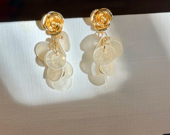 Brincos pendentes artesanais em concha natural espelhada, banhados a ouro 14k, design delicado.