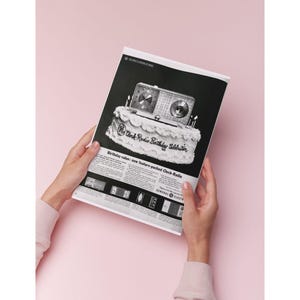 Puede incluir: Anuncio vintage en blanco y negro de un radio reloj, presentado como una tarta de cumpleaños. El texto dice "Clock Radio Birthday Celebration" y "Birthday value: new feature-packed Clock-Radio". El fondo es rosa pálido.