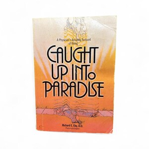 May include: A vintage book cover with the title "CAUGHT UP INTO PARADISE" in large, bold letters. The cover features an illustration of a person lying down, with a bright orange and yellow background. The author's name, Richard E. Eby, D.O., is also visible.