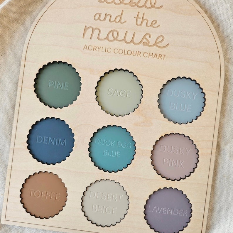 May include: A wooden colour chart with 10 paint swatches in different colours. The colours are labelled: Pine, Sage, Dusky Blue, Denim, Duck Egg Blue, Dusky Pink, Toffee, Desert Beige, and Lavender. The chart is titled "and the mouse Acrylic Colour Chart".