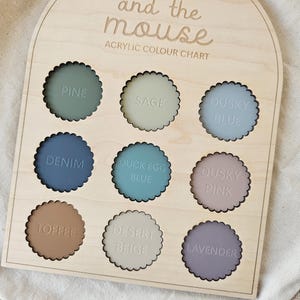 May include: Wooden color chart with nine scalloped acrylic color samples. The colors include Pine, Sage, Dusky Blue, Denim, Duck Egg Blue, Dusky Pink, Toffee, Desert Beige, and Lavender. The text "koko and the mouse" and "ACRYLIC COLOUR CHART" are engraved on the wood.