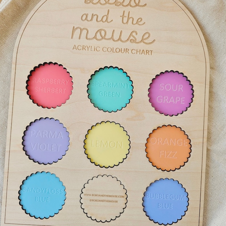 May include: A wooden colour chart with the words "Bobo and the Mouse" and "Acrylic Colour Chart" printed on it. The chart features nine round paint swatches in various colours, including raspberry sherbet, spearmint green, sour grape, parma violet, lemon, orange fizz, candy floss blue, and bubblegum blue.