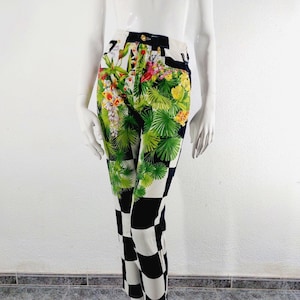 May include: High-waisted jeans with a black and white checkered pattern on the bottom half and a floral print on the top half. The floral print features tropical leaves, flowers, and birds.
