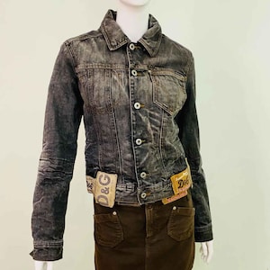 Puede incluir: Chaqueta vaquera gris oscuro con una minifalda marrón a juego. La chaqueta tiene botones y dos bolsillos delanteros. La falda tiene dos bolsillos delanteros. Ambos artículos tienen etiquetas D&G.