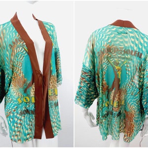 May include: A turquoise and brown patterned kimono with a brown satin trim and the text "Amour Soleil" on the back.