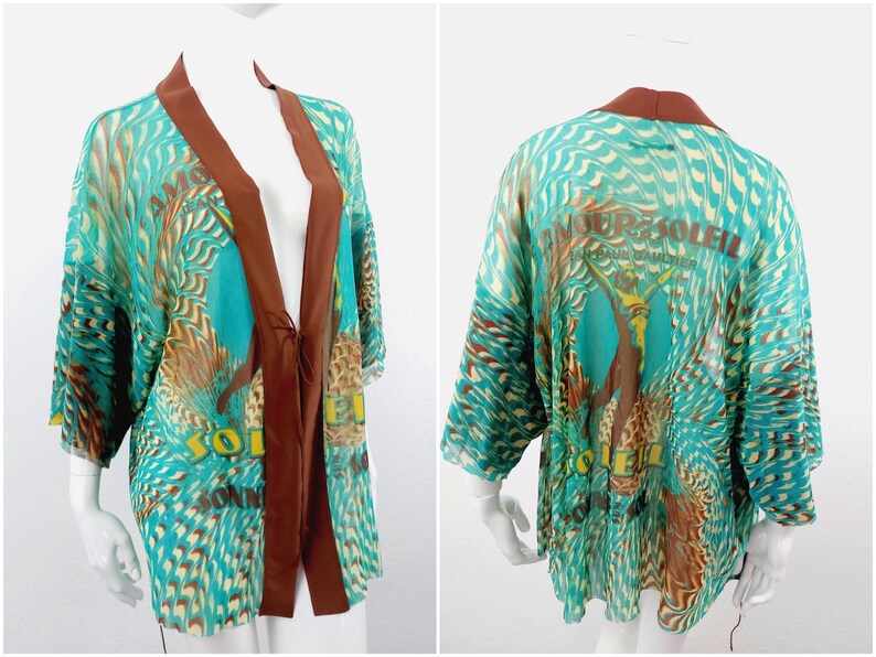 May include: A turquoise and brown patterned kimono with a brown satin trim and the text "Amour Soleil" on the back.