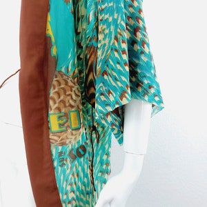 May include: A turquoise and brown patterned kimono with a brown trim. The kimono has a tie closure at the neck.