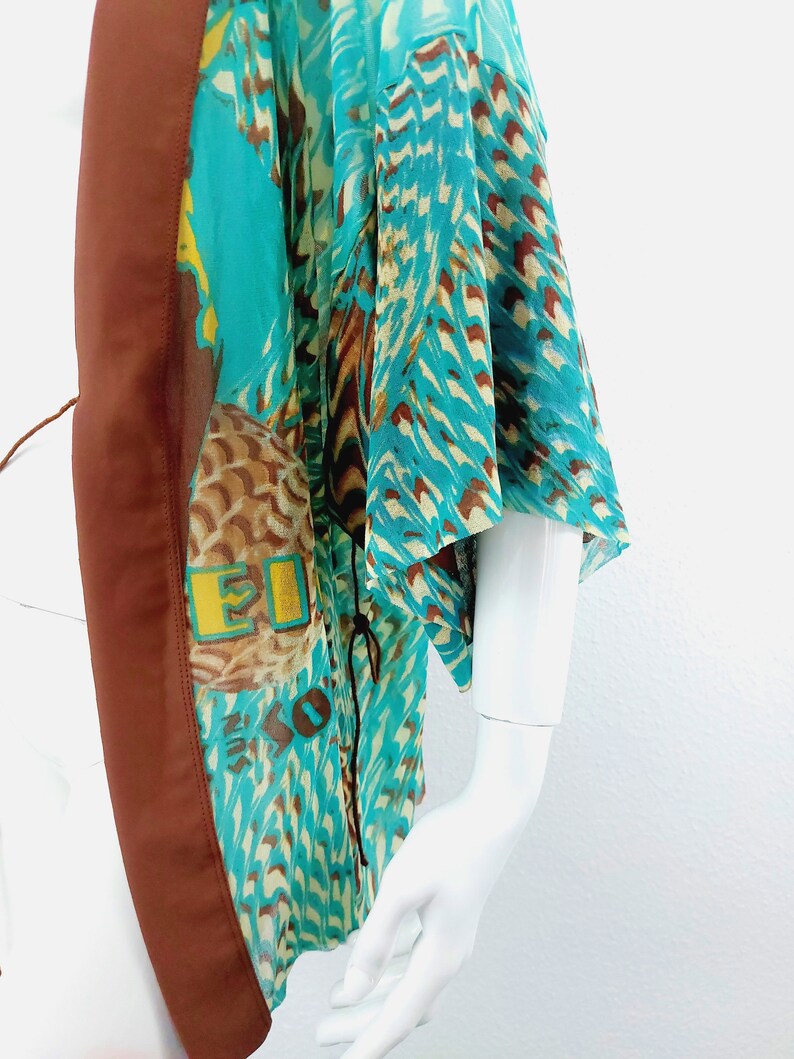 May include: A turquoise and brown patterned kimono with a brown trim. The kimono has a tie closure at the neck.