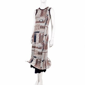 May include: A sleeveless midi dress featuring a beige and brown graphic print of city buildings and figures. The dress has a dark brown trim around the neckline and armholes, and it is layered over a solid black skirt that extends below the hem.