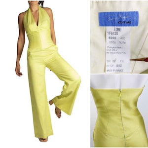 May include: A light yellow halter-neck jumpsuit with wide-leg pants. The outfit features a fitted bodice and a label with text including "COUTURE" and "MADE IN FRANCE".